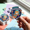 Custom die-cut white vinyl stickers cut perfectly to shape, stacked on a colorful background for promotional event swag.