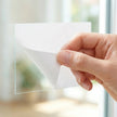 Custom removable white BOPP roll labels peeling cleanly off a glass window with absolutely no sticky residue left behind.
